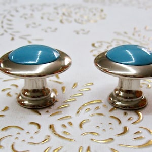 以下が含まれることがあります： ターコイズブルーのセラミックトップが付いたシルバーのキャビネットノブ2個。