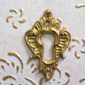 Peut inclure: Un cache-trou de serrure en or avec un design orné. Le cache est en métal et présente un motif décoratif complexe.