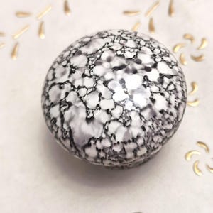 May include: A white ceramic knob with a black and gray marbled pattern.