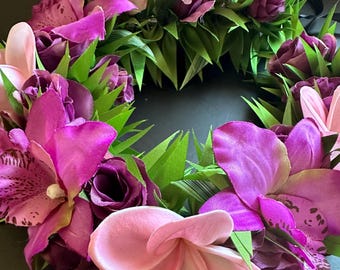 May include: A pink and purple flower lei with green leaves. The lei is made of silk flowers and is perfect for a luau or other tropical event.