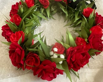 May include: A red rose lei with green leaves and white flowers. The lei is made of silk flowers and is perfect for a special occasion.