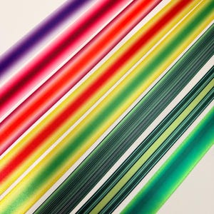 May include: Diagonal view of colorful ribbons in shades of purple, red, yellow, and green. The ribbons are arranged in parallel lines, creating a vibrant and eye-catching display. The ribbons have a glossy finish.