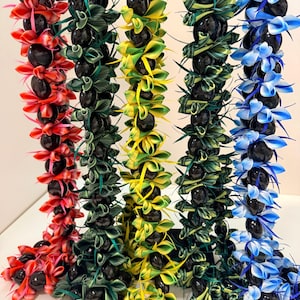 Pu&ograve; includere: Una collezione di collane di fiori colorate, ognuna con una combinazione unica di nastri vibranti e perline scure e rotonde. Le collane sono esposte in tonalit&agrave; di rosso, verde, giallo e blu, creando una disposizione visivamente sorprendente e festosa.