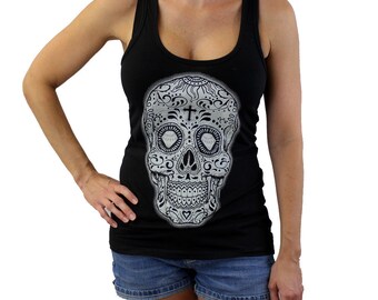 May include: Black tank top with a white sugar skull graphic. The skull has intricate details and a cross on its forehead.