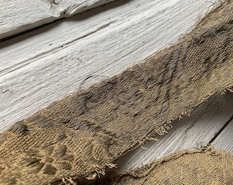 May include: Close-up of a brown, woven fabric with a frayed edge. The fabric has a textured, wavy pattern.