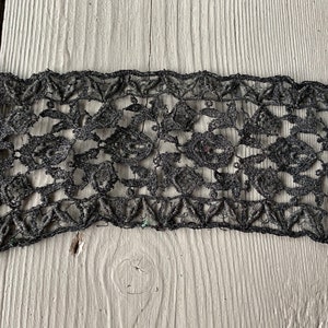 May include: Black lace trim with a floral pattern. The lace is delicate and intricate.