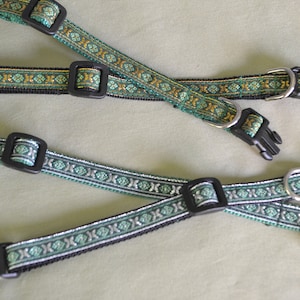 May include: Three green and gold patterned dog collars with black buckles and silver rings. One collar has a small bell attached.
