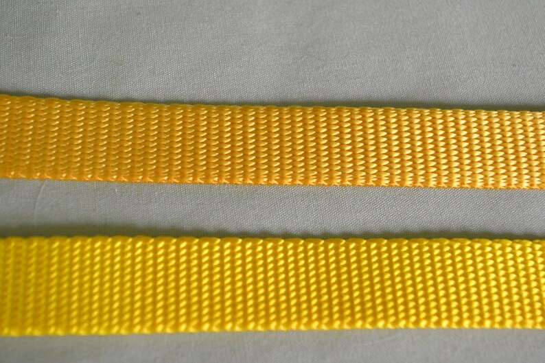 May include: Two pieces of yellow webbing, one slightly darker than the other, are shown side-by-side. The webbing is woven with a textured pattern.
