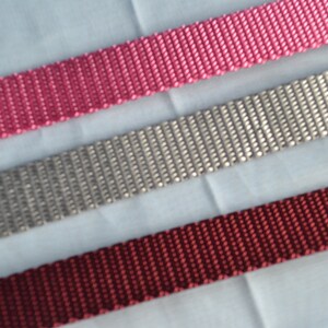 May include: Three different colors of woven webbing, pink, gray, and burgundy.