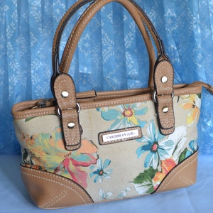 Bolso de mano Caribbean Joe. Tejido floral con piel sintética color canela en la parte inferior, las esquinas, el borde superior y las asas dobles.