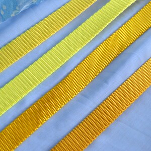 May include: Four different widths of yellow and lime green webbing, laid out on a blue fabric background.
