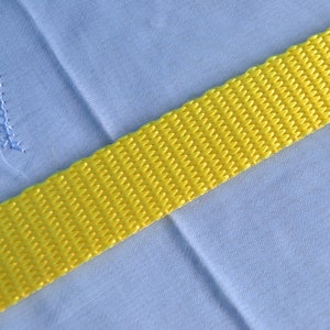 May include: A yellow woven strap against a light blue background.