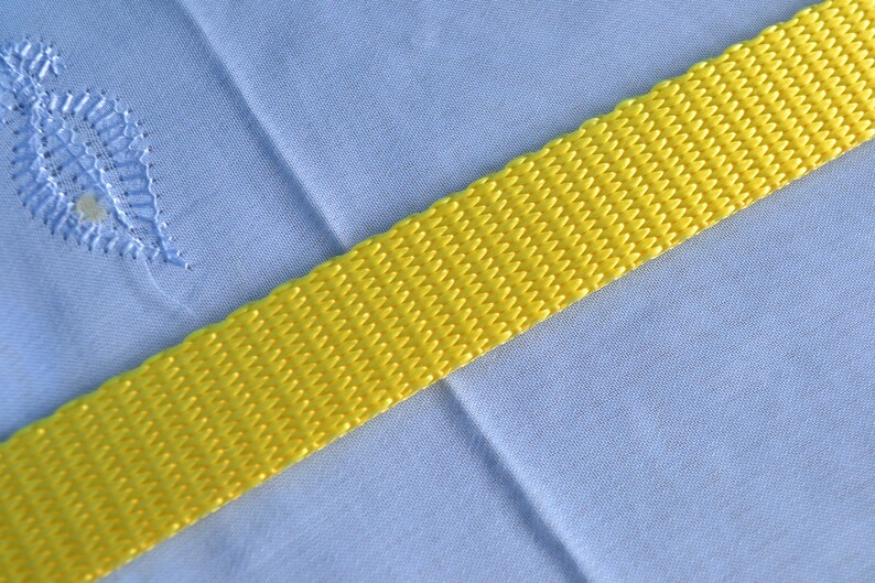 May include: A yellow woven strap against a light blue background.