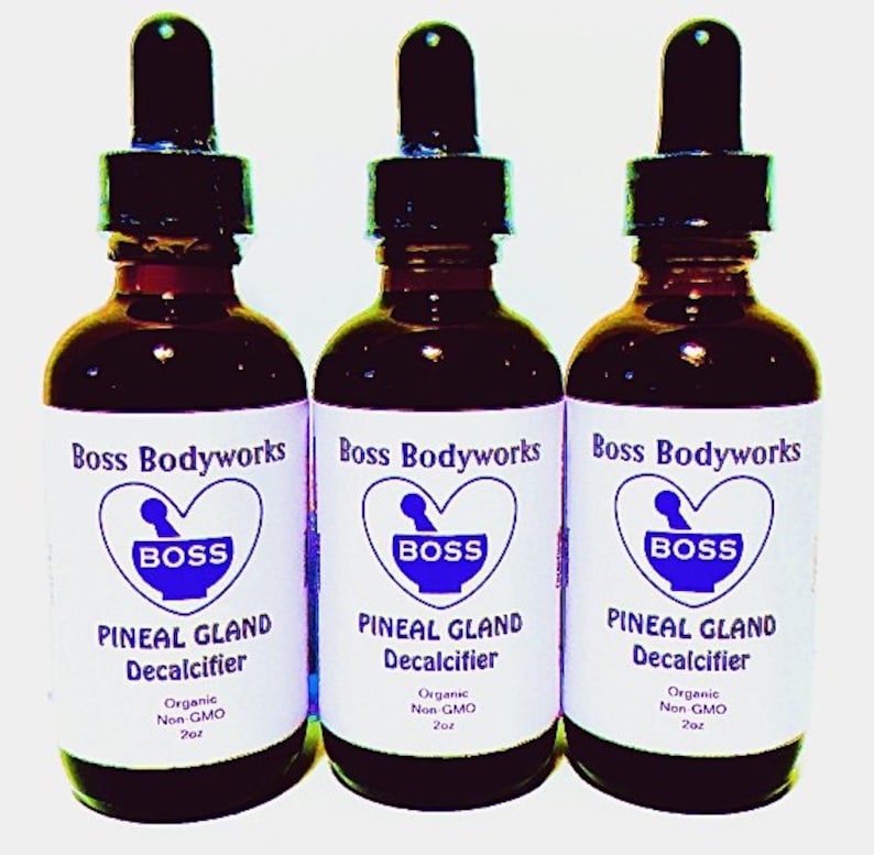 Op de afbeelding: Drie glazen flessen met druppelaars, elk gevuld met een donkere vloeistof. De flessen zijn gelabeld met "Boss Bodyworks" en "Pineal Gland Decalcifier". De etiketten zijn wit met blauwe tekst en een blauw hartvormig logo met het woord "BOSS" erin.