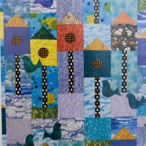 May include: A colorful quilt with a patchwork design featuring birdhouses and birds. The quilt is made up of various fabrics in shades of blue, green, yellow, red, and purple. The birdhouses are decorated with different patterns and designs.
