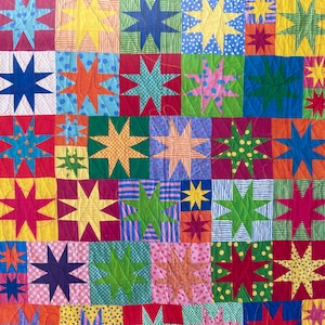 May include: A colorful quilt with a patchwork design featuring various shades of red, green, blue, yellow, and orange. Each square of the quilt is decorated with a star-shaped pattern.