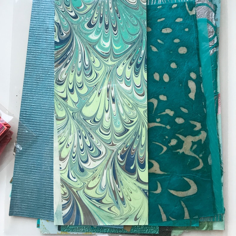 May include: A collection of patterned paper in shades of teal, green, and white. The paper has a marbled, speckled, and textured look.