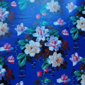 May include: A blue background with a repeating pattern of white and pink flowers. The flowers have a vintage style and are surrounded by green leaves.