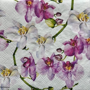 May include: White paper napkin with a floral pattern of pink and white orchids. The orchids are painted in a watercolor style and have a delicate, feminine look.