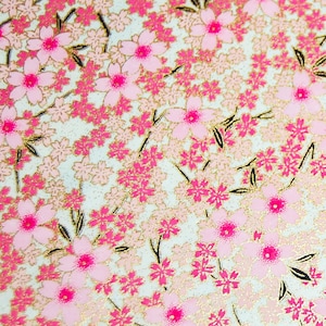 May include: A close-up of a pink and gold floral pattern on a white background. The pattern features small pink flowers with gold accents.