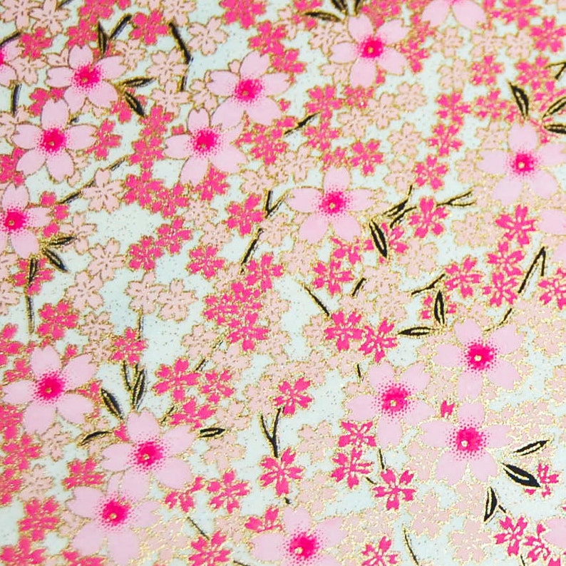May include: A close-up of a pink and gold floral pattern on a white background. The pattern features small pink flowers with gold accents.