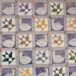 May include: A quilt with a purple background and a repeating pattern of white geese and colorful patchwork stars. The quilt is made up of squares with different designs.
