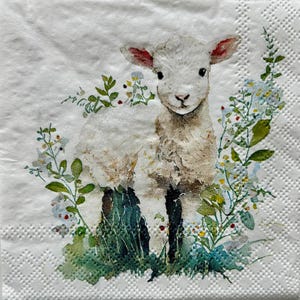 May include: A white lamb with pink-lined ears and black eyes is surrounded by greenery and small white and yellow flowers. The lamb is standing on green grass. The image is printed on a white, textured paper napkin.