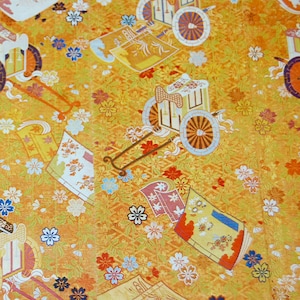 May include: A yellow fabric with a repeating pattern of stylized carriages and flowers. The carriages are drawn by horses and have wheels with intricate designs. The flowers are in shades of pink, white, and blue.
