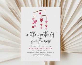 May include: A pink and white baby shower invitation with a watercolor illustration of a mobile with hearts. The text reads "a little sweetheart is on the way!" and includes details for the event, such as the date, time, and location.