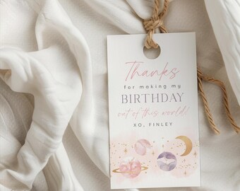 May include: Pink and gold thank you tag with a space theme. The tag says "Thanks for making my birthday out of this world! XO, Finley".
