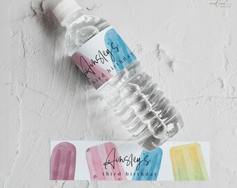 May include: Water bottle label with a watercolor design of popsicles in pink, blue, and yellow. The text on the label reads "Ainsley's third birthday".
