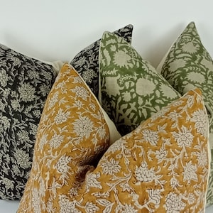May include: Four decorative throw pillows with floral patterns. The pillows are in shades of black, green, and mustard yellow.