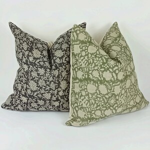 May include: Two decorative throw pillows with floral patterns. One pillow is green with a white floral pattern, and the other is black with a white floral pattern.