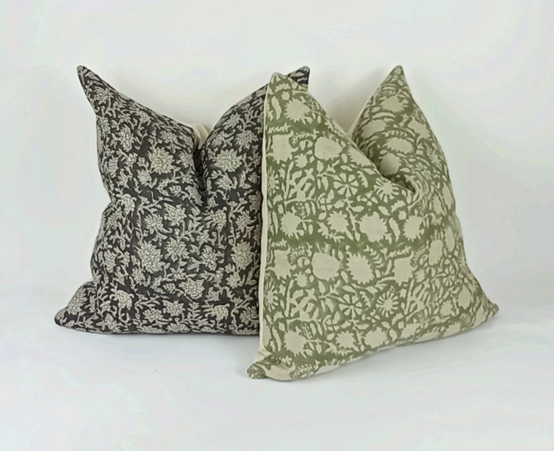 May include: Two decorative throw pillows with floral patterns. One pillow is green with a white floral pattern, and the other is black with a white floral pattern.