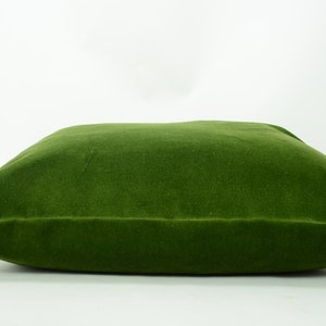 May include: A large, square, green velvet pillow. The pillow is soft and plush, and would be perfect for adding a touch of color and comfort to any room.