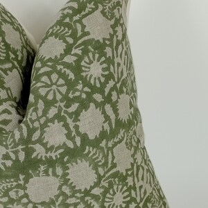 May include: A green and beige patterned pillow with a floral design. The pillow is made of a soft, linen fabric.