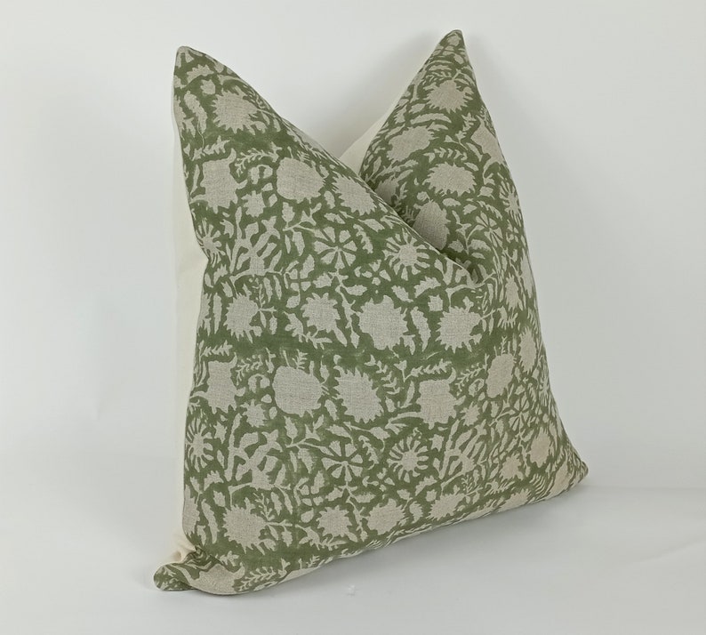 May include: A green and white patterned throw pillow with a floral design. The pillow is made of a soft, linen fabric.