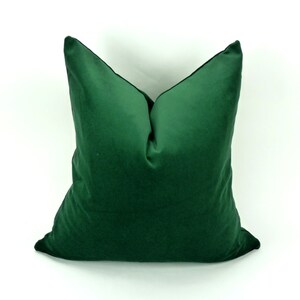 May include: A deep green velvet pillow with a square shape. The pillow is made of a soft, plush fabric.