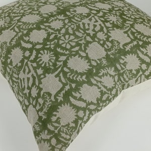 May include: A green and white floral patterned throw pillow with a white border.