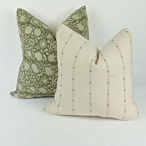 May include: Two decorative throw pillows, one with a green floral pattern and the other with a white background and brown stripes.