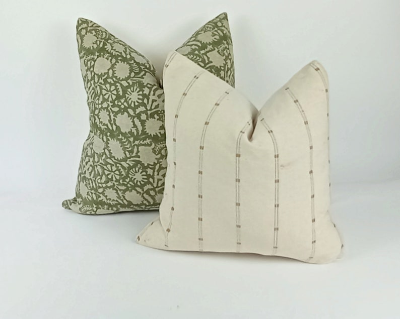 May include: Two decorative throw pillows, one with a green floral pattern and the other with a white background and brown stripes.