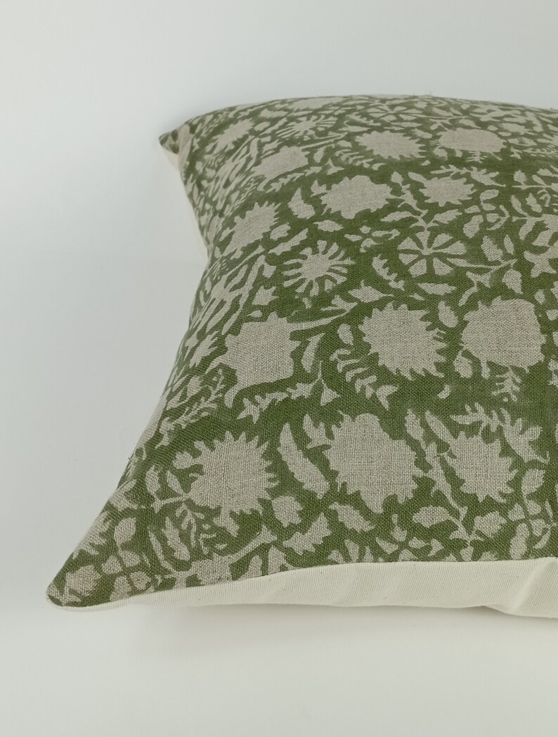 May include: A green and white patterned throw pillow with a floral design. The pillow is made of a soft, linen-like fabric.