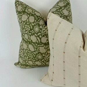 May include: Two decorative throw pillows, one with a green floral pattern and the other with a white background and thin brown stripes.