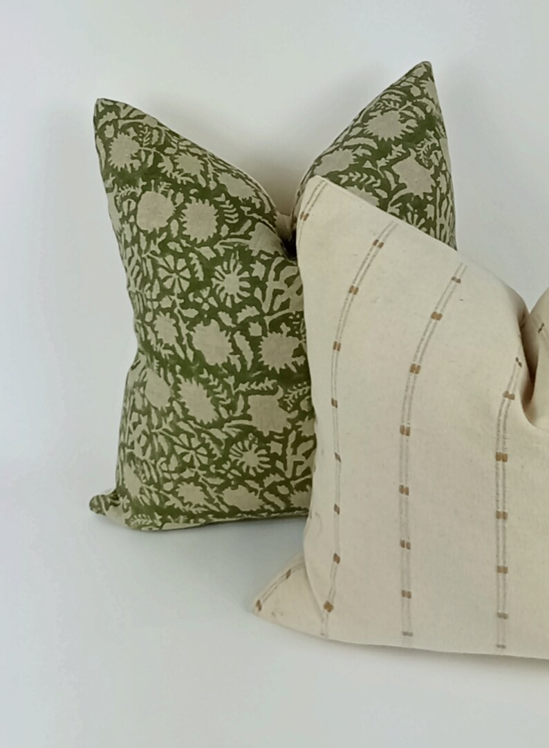 May include: Two decorative throw pillows, one with a green floral pattern and the other with a white background and thin brown stripes.