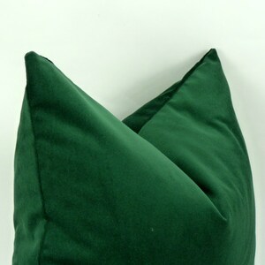 May include: Two green velvet pillow covers, folded in half and placed on a white background.