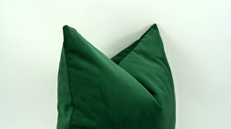 May include: Two green velvet pillow covers, folded in half and placed on a white background.