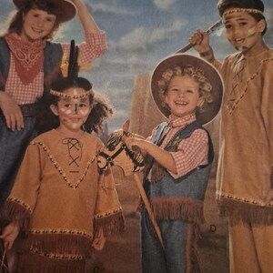 May include: A sewing pattern illustration featuring four children in costumes. Two children wear tan fringed tunics with lace-up necklines and headbands. Two children wear cowboy outfits with plaid shirts, denim vests, fringed chaps, and brown hats.