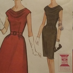 Puede incluir: Patrón de costura vintage de McCall's con dos diseños de vestidos. Uno es un vestido rojo hasta la rodilla con cinturón. El otro es un vestido negro hasta la rodilla con cinturón. Ambos vestidos tienen cuello redondo y mangas cortas.