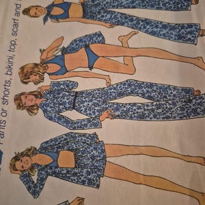 May include: A sewing pattern envelope featuring illustrations of pants, shorts, a bikini, a top, a scarf, and a tote bag. The garments display a blue and white floral pattern. The text on the side reads: Pants or shorts, bikini, top, scarf and tote bag.