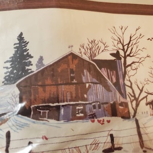 May include: A stamped design on fabric depicting a winter barn scene. The image shows a barn, silo, and snow-covered landscape. The design includes text: "Stamped design on 50% cotton/50% polyester fabric; 100% wool thread; needles; easy-to-follow instructions. Frame not included."